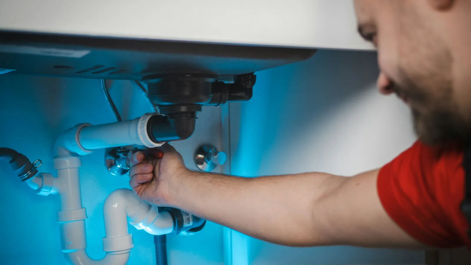 Plumber connecting water lines under a kitchen sink