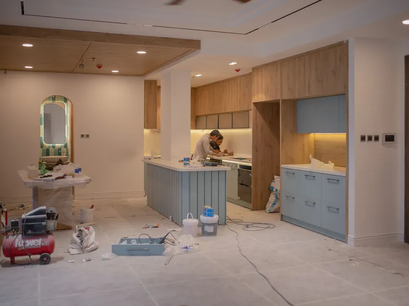 Kitchen under renovation with a worker finishing cabinetry