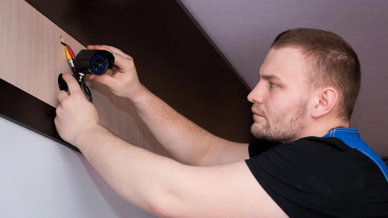 Technician mounting a security camera on an interior wall
