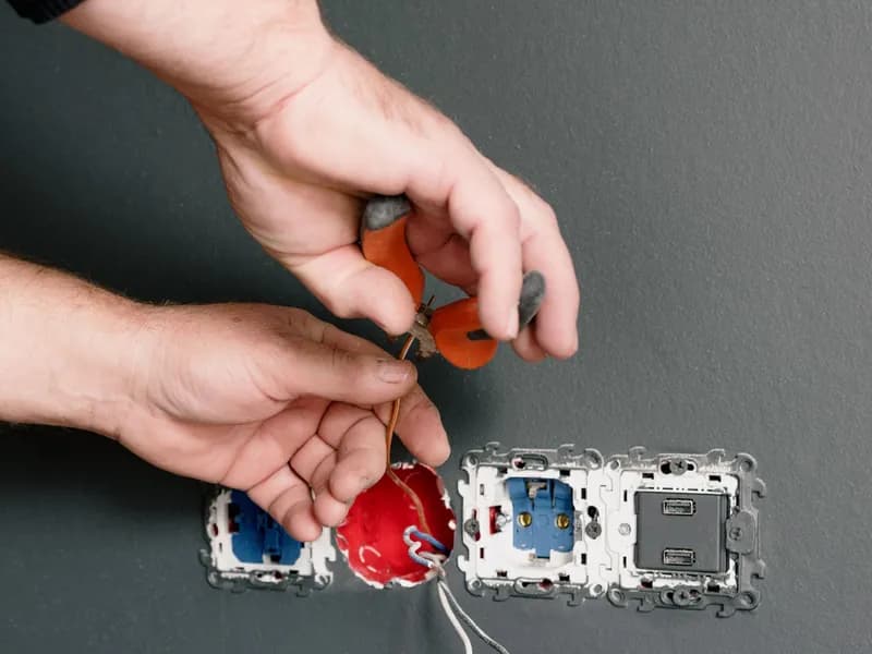 Electrician wiring switches and outlets in a wall box