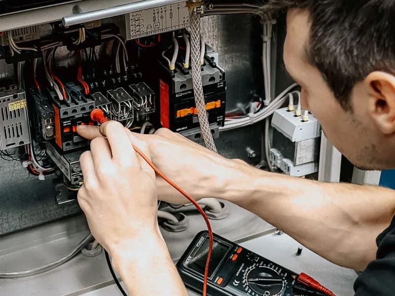 Electrician testing panel wiring with a multimeter