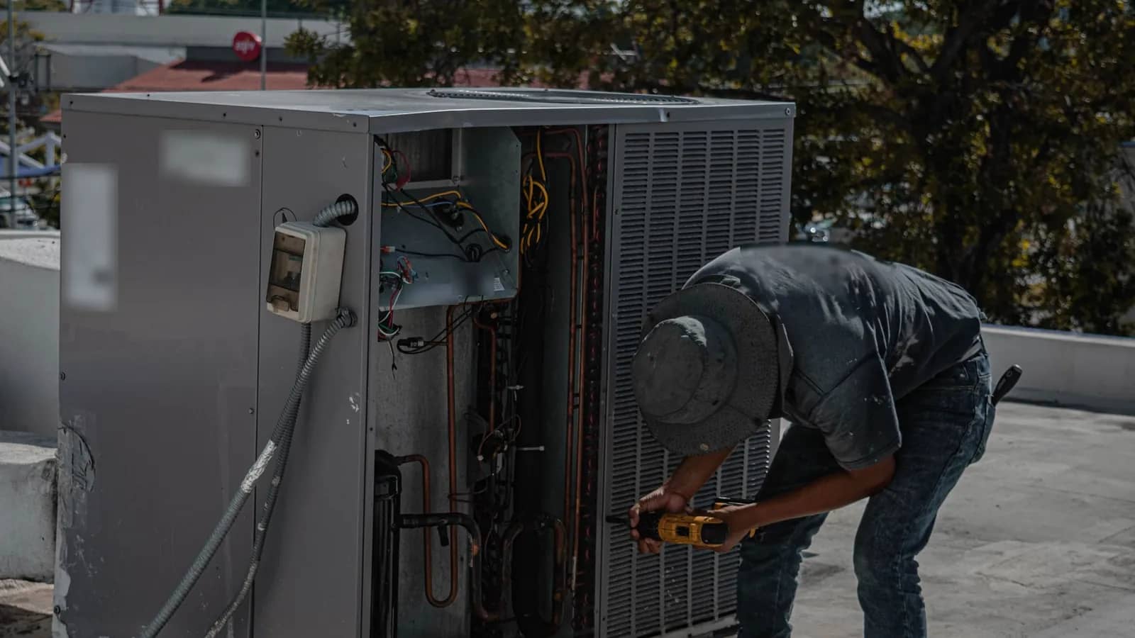 HVAC technician servicing the wiring and coil of an outdoor condenser unit