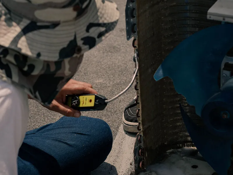Technician testing an outdoor air conditioning unit with a multimeter